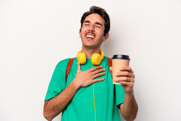 Young caucasian student man drinking coffee isolated on white background laughs out loudly keeping hand on chest.