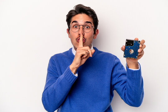 Young caucasian informatic man holding a hard disc drive isolated on white background keeping a secret or asking for silence.