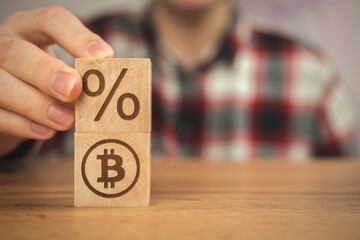 Bitcoin and taxes concept background, us taxation. Wooden cubes with bitcoin and percent symbols in hands close-up view business photo