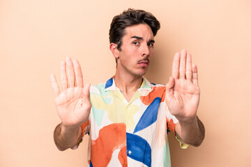 Young caucasian man isolated on beige background standing with outstretched hand showing stop sign,...