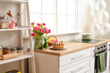 Easter cake, basket of eggs and tulips on kitchen counter