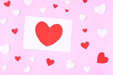 White greeting card with heart papercut on pink background