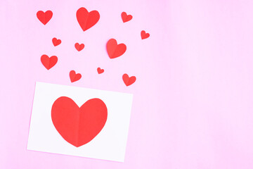 White greeting card with heart papercut on pink background