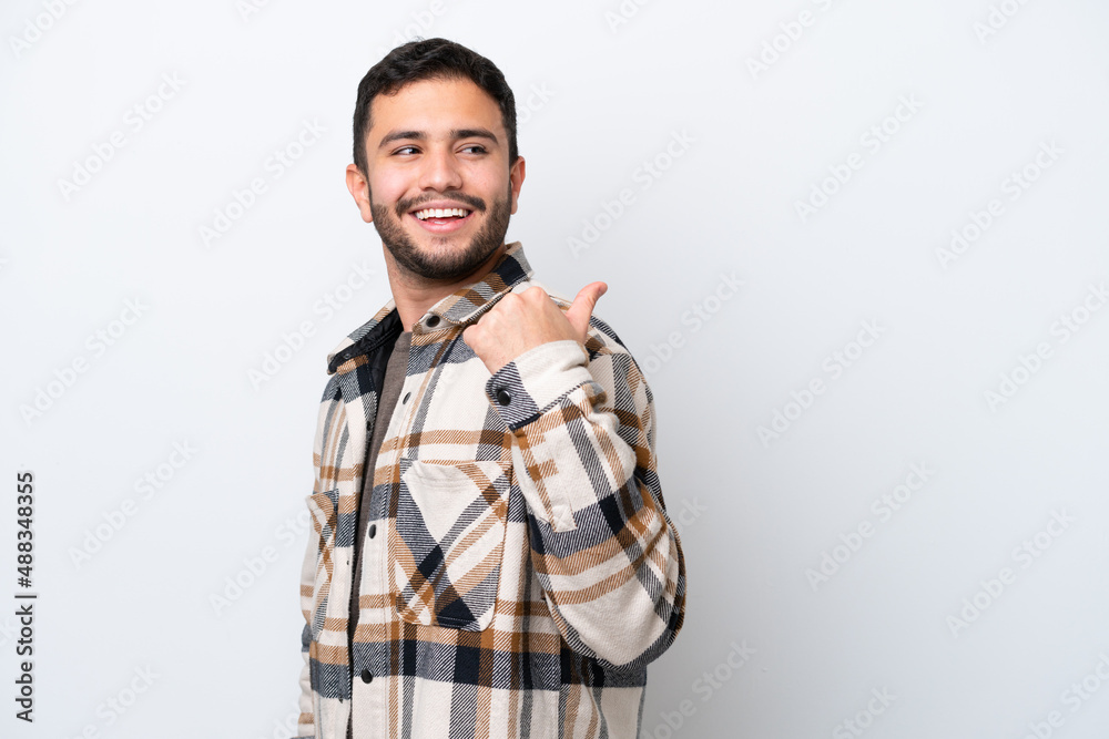 Wall mural Young Brazilian man isolated on white background pointing to the side to present a product