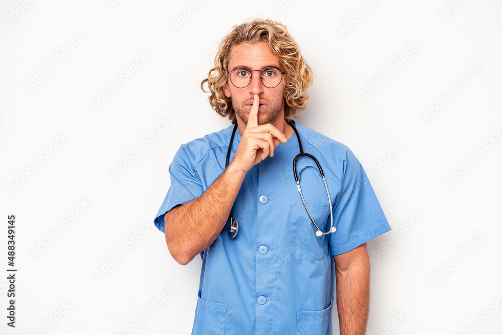 Wall mural Young nurse caucasian man isolated on white background keeping a secret or asking for silence.