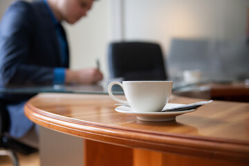 white cup of coffee on an office desk, business meeting concept