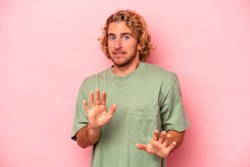 Young caucasian man isolated on pink background rejecting someone showing a gesture of disgust.