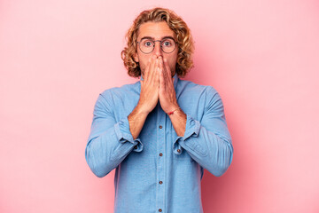 Young caucasian man isolated on pink background shocked covering mouth with hands.