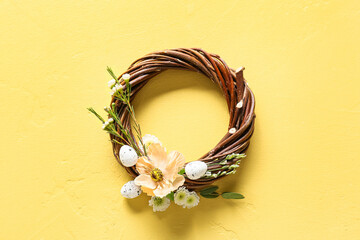 Beautiful Easter wreath with eggs and flowers on yellow background