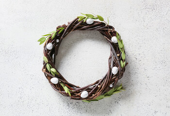 Beautiful Easter wreath with eggs and green branches on light background