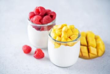 Set of Greek yogurt mango and raspberry parfait in jars