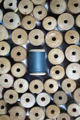 Wooden spools of thread are laid out around a blue bobbin of thread. A pattern of antique sewing accessories. Top view, close-up, macro..