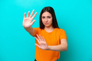 Young caucasian woman isolated on blue background nervous stretching hands to the front