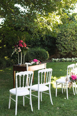 White garden chairs with flower bouquet at wedding reception in a garden in Lombardy, Italy during the summer