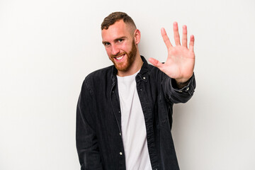 Young caucasian man isolated on white background smiling cheerful showing number five with fingers.