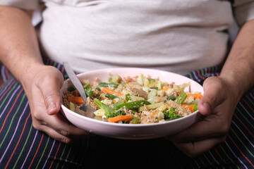  a fat men in casual dress eating fresh salad , healthy food concept 