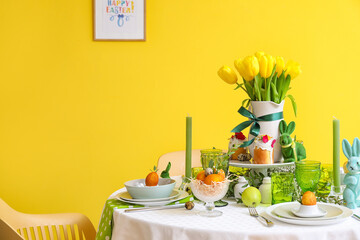 Stylish dinnerware on table served for Easter celebration near color wall