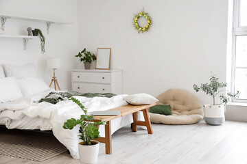 Interior of light bedroom with Easter wreath and houseplants