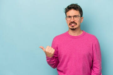 Fototapeta premium Young caucasian man isolated on blue background shocked pointing with index fingers to a copy space.