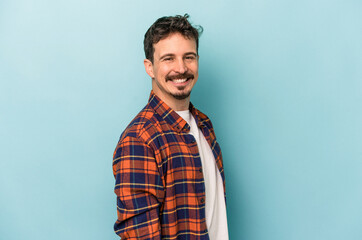 Fototapeta premium Young caucasian man isolated on blue background confident keeping hands on hips.