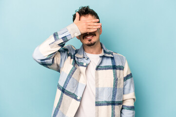 Young caucasian man isolated on blue background covers eyes with hands, smiles broadly waiting for a surprise.