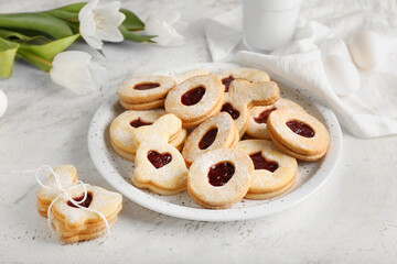 Plate with delicious Easter cookies on light background