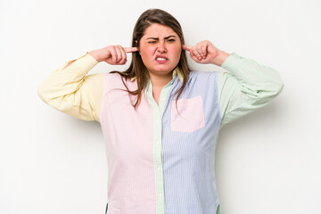 Young caucasian overweight woman isolated on white background covering ears with fingers, stressed and desperate by a loudly ambient.