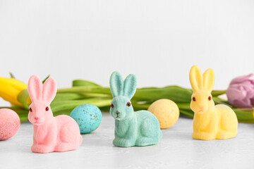 Different Easter bunnies and eggs on light background