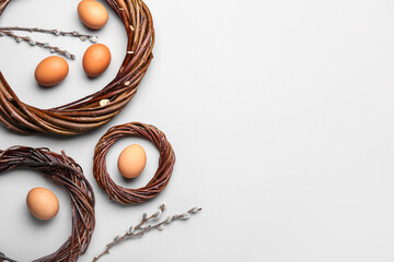 Nests with Easter eggs and willow branches on light background