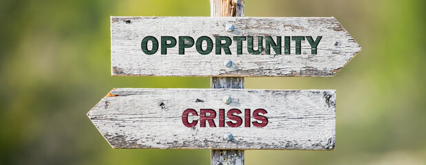 opposite signs on wooden signpost with the text quote opportunity crisis engraved. Web banner format.