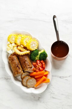 Chicken galantine, sliced, served on white plate with bbq sauce and vegetables. Selective focus