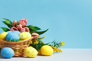 Easter concept. Basket of eggs flowers on a blue background copy space.