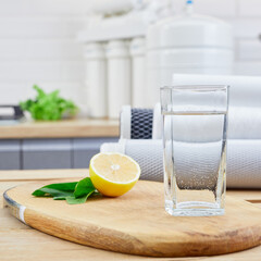 Glass of clean filtered water with lemon and ice in kitchen. Breakfast, fresh morning drink.