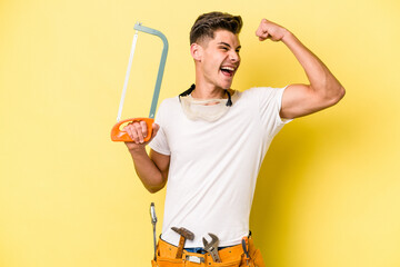 Young electrician caucasian man isolated on yellow background.raising fist after a victory, winner...