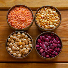 Four bowls with various legumes: lentils, peas, chickpeas, red beans