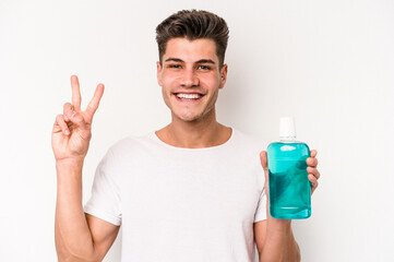 Young caucasian man holding mouthwash isolated on white background showing number two with fingers.