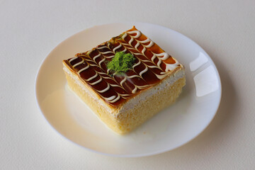 Trilece dessert with caramel in a white plate. Traditional Turkish cuisine flavor.