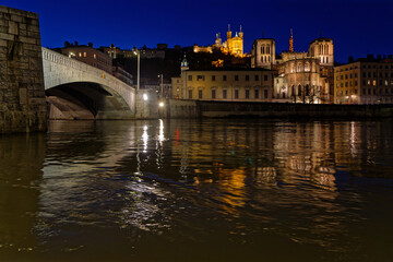 LYON, FRANCE, February 19, 2022 : St-Jean Cathedral, Fourviere basilica and Bonaparte bridge reflect in the waters of Saone river at the blue hour.
