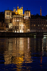 Fototapeta na wymiar LYON, FRANCE, February 19, 2022 : St-Jean Cathedral and Fourviere basilica reflect in the waters of Saone river at the blue hour.