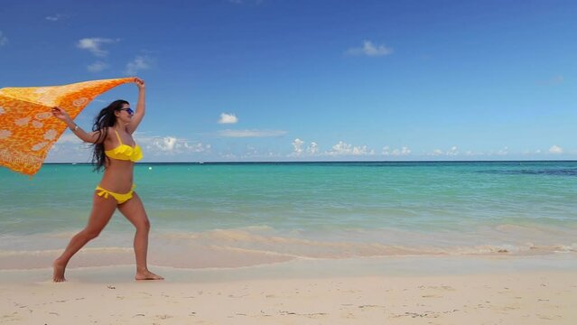 Happy woman with a yellow scarf on tropical beach. Vacation on exotic island.