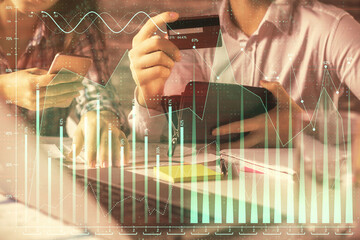 Double exposure of man and woman on-line shopping holding a credit card and forex graph hologram drawing. Stock market E-commerce pay on-line concept.