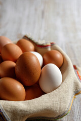 Close-up view of brown and white chicken eggs, in a wicker basket on gray wood. Vertical view.