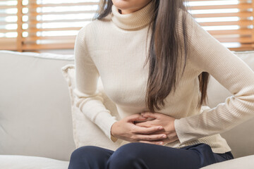 Flatulence asian young woman, girl hand in stomach ache, suffer from food poisoning, abdominal pain and colon problem, gastritis or diarrhoea. Patient belly, abdomen or inflammation, concept.