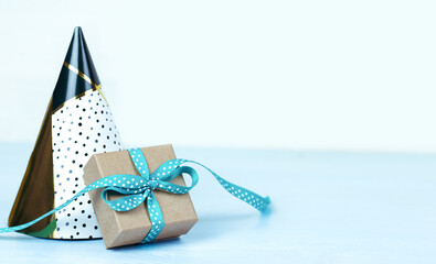 Festive caps and a gift box with a bright blue bow stand on a blue wooden table. Birthday concept