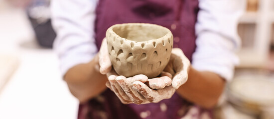 Pottery artist showing completed artwork clay vase in ceramic studio. Woman hands. Creative people, handmade crafts.