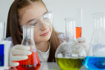 child girl science students study research liquid chemical experiments in white laboratory room. schoolgirl holding test tube with learning biotechnology. science education cocept.