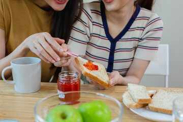 happy asian female couple have breakfast at table kitchen. two beautiful woman eating food in the morning.