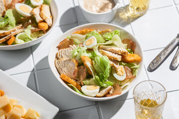 Caesar salad with chicken in a plate on a light background