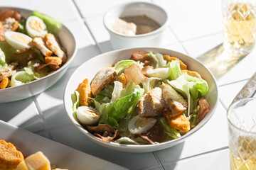 Caesar salad with chicken in a plate on a light background