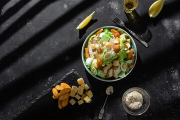 Caesar salad with chicken in a plate on a dark background - obrazy, fototapety, plakaty